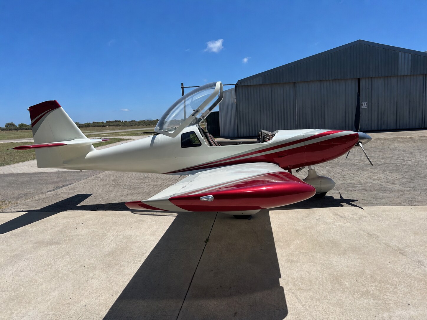 Side view of a red and white Whisper X350 with an empty cockpit